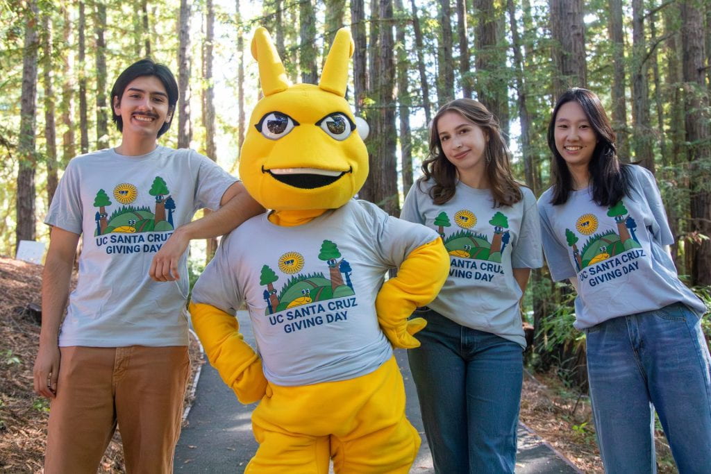 Three students posing the the mascot, Sammy the Slug.